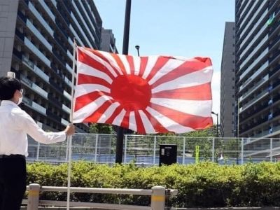 Пикетчик с флагом императорской армии Японии у Олимпийской деревни. Фото: Yonap News