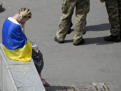 Девушка сидит на площади Майдана во время панихиды по активисту и солдату Роману Ратушному,18 июня 2022 года. Фото: Natasha Pisarenko / AP